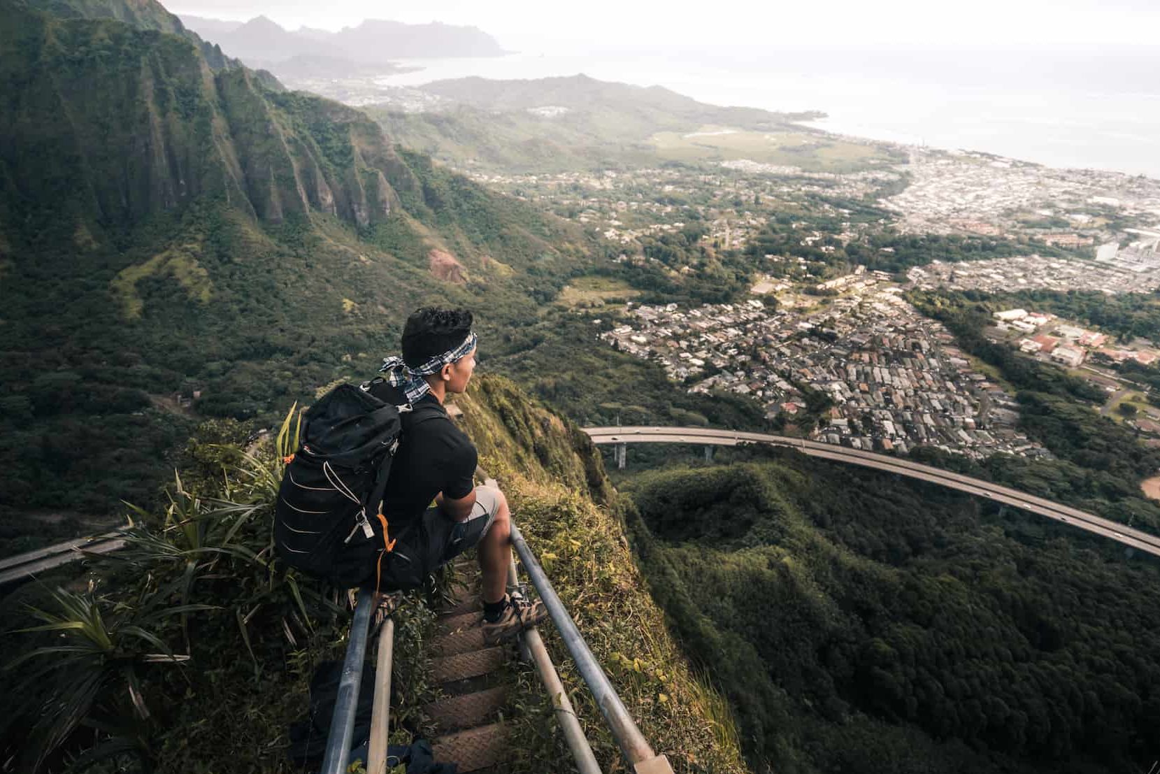 Fearless Elopement Traveling Photographer Sam Sansudsavat Sitting on mountain stair handrails with a beautiful view of a city