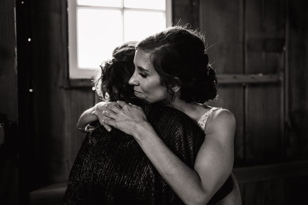 bride and her mom hugging before walking down the aisle at a wedding