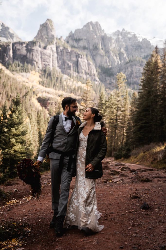 elopement Photo of Bride and Groom Traveling along dirt pathway of forest and mountain in background