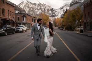 Wedding photo of Bride and Groom staring at each other walking down an open road holding hands on a small town in the country side
