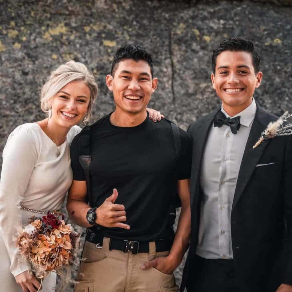 bride in white dress and groom in suit standing and smiling next to Arizona wedding photographer.