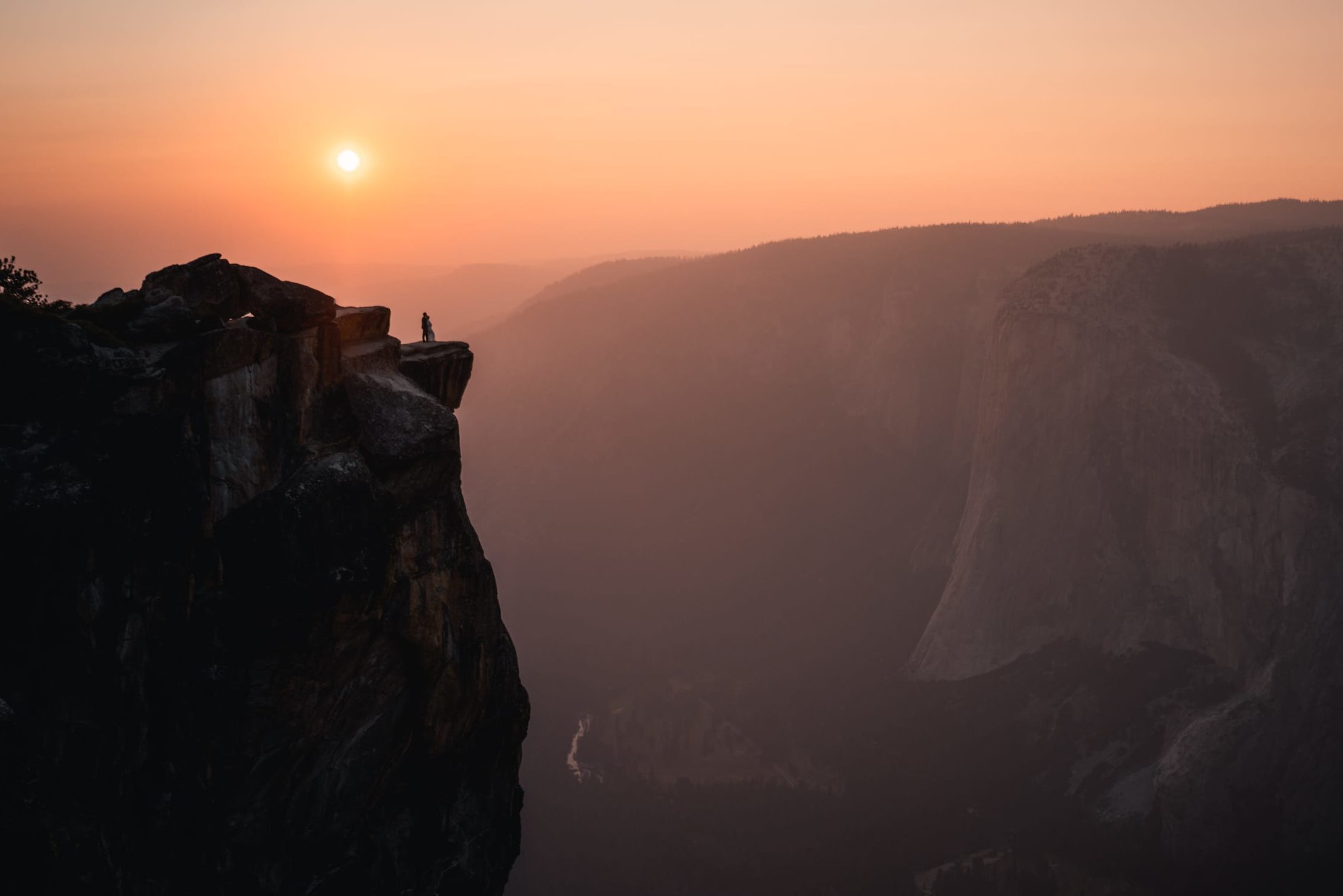 Distant photo of a person on a mountain cliff view with beautiful sunset