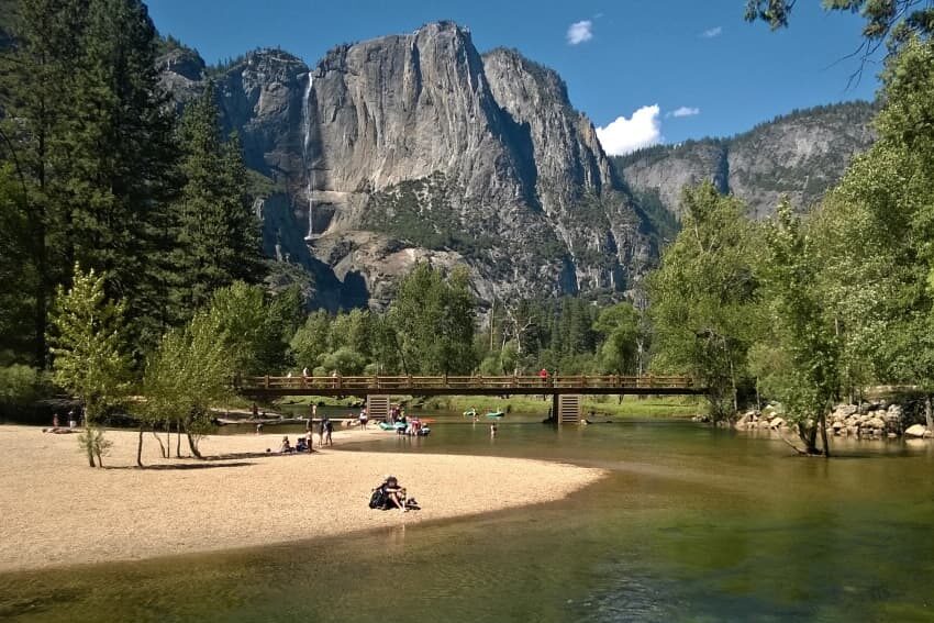 Sentinel Beach and Cascade Picnic Area in Yosemite National Park, with the Merced River flowing gently in the foreground, sandy shores for beachgoers, and the towering granite cliffs of Yosemite Valley in the background